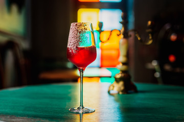 A cocktail in a wine glass with an ice cube