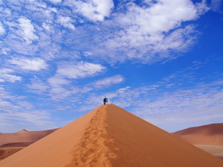 Fototapeta na wymiar A woman barefoot up a beautiful sand Dune 45, Namibia