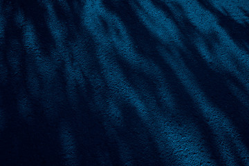 Navy blue abstract background with spots. Tree shadow pattern on asphalt at night. Toned dark blue grunge background. Shadow on the sidewalk. Light and shadow on a concrete stone surface.