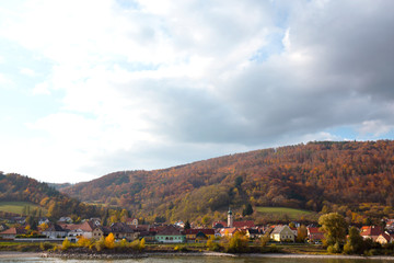 autumn view of small austrian village on a river bank
