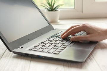 Young adult sitting in freelance home office with black laptop