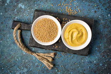 Set of yellow mustard sauce and seeds in small bowls