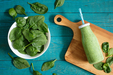 Fresh spinach and a smoothie on a blue table