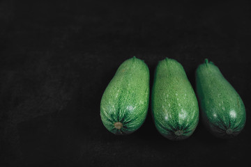 Three zucchini on a dark background. Organic eco food. Healthy diet. Freshly picked vegetables. Fresh greens for salad. Natural organic food. Edible vegetable background