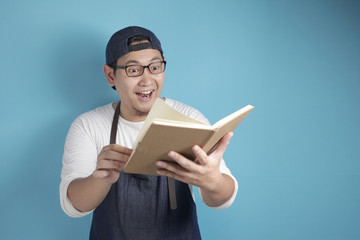 Portrait of Asian male chef reading book of recipes, finding secret recipe