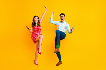 Full length photo attractive lady handsome guy couple hold telephones win lottery online scream achievement wear red dotted dress shirt bowtie retro clothes isolated yellow color background