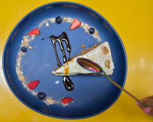 Metal spoon dipping into a carrot cake with walnuts and icing sugar, decorated with strawberries,...