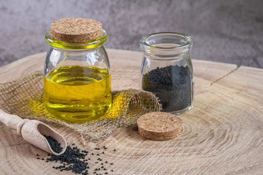 Black cumin seeds with oil on wooden background