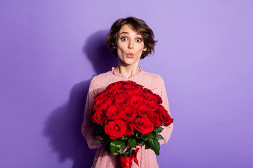 Portrait of nice-looking attractive lovely pretty charming amazed cheerful girl holding in hands roses sudden delivery isolated on bright vivid shine vibrant lilac violet purple color background