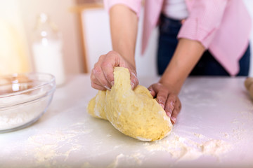 Close up of female baker hands kneading dough and making bread. cooking and home concept - close up of female hands kneading dough at home