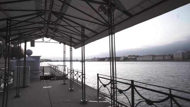 frame with a pier on the river and buildings on the shore.