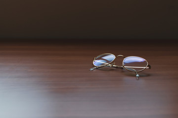 Fototapeta na wymiar Clear Eyeglasses Glasses with Gold Frame Fashion Vintage Style on Wood Desk Background, Rustic Still Life Style.