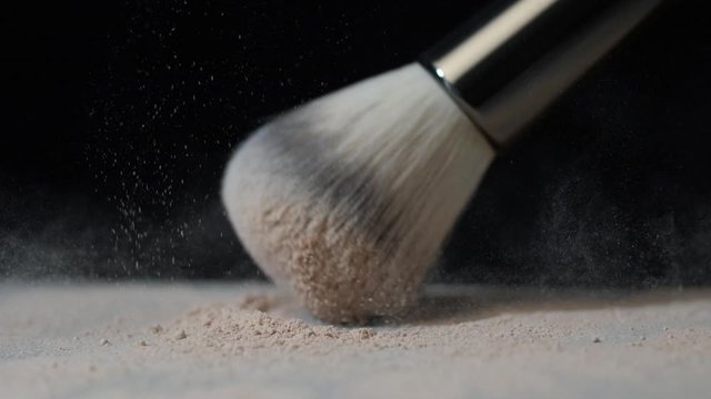 Close up of makeup brush. Buy hit on powder. Slow motion.
