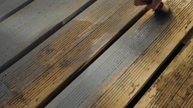 A shot of a caucasian female doing DIY and painting decking boards