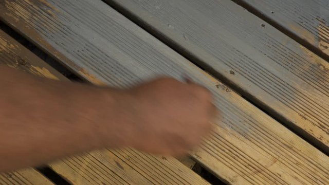 A shot of a black painting contractor painting decking boards 