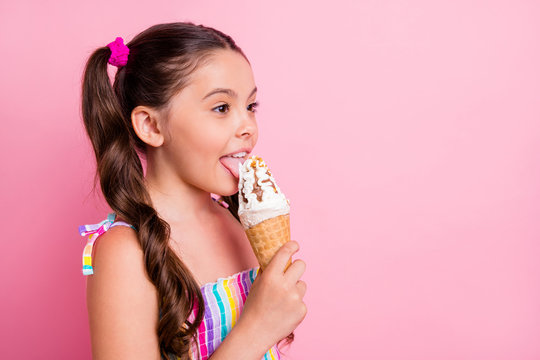 Profile photo of beautiful little lady two cute long tails hold big cone ice cream delicious dessert lick tongue try vanilla taste wear summer dress isolated pastel pink color background