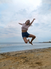 Fototapeta na wymiar flying jump beach girl on blue sea shore in summer vacation