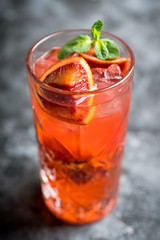 Red cocktail with blood oranges and mint on the rustic background. Selective focus. Shallow depth of field.
