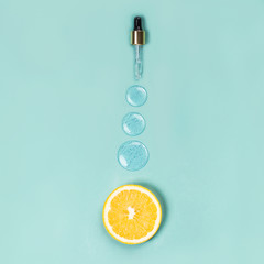 A slice of orange and three round drops of liquid gel on a blue background Medical concept Vitamin...