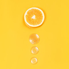 Orange slice and three round drops liquid gel on an orange background Vitamin C medical concept...