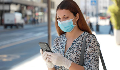 COVID-19 Woman Wearing Surgical Mask and Protective Gloves Using Mobile Phone Application in City Street to Aid Contact Tracing and Self Diagnostic in Response to SARS-CoV-2