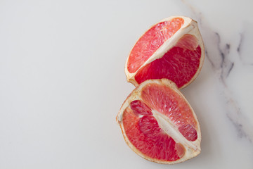 Quarters flat layout of grapefruit slices on marble and blue loaf close-up, top view with copy space