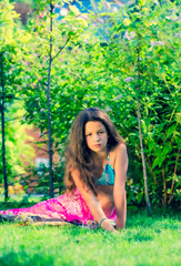 Naklejka na ściany i meble Model looking Girl standing in a swimsuit on the background of green grass and forest. Copy space