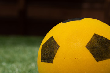 closeup of a bright yellow kids football on a grass background in a garden