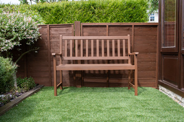 Empty brown garden bench set in a English garden on perfect fake grass