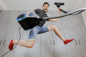 House cleaning. Jumping man with vacuum cleaner. Сleaned apartment
