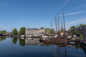 Fototapeta na wymiar Museum harbor and Turfsingelgracht in Gouda with historic boats, De Roode Leeuw flour mill and the Gouwekerk