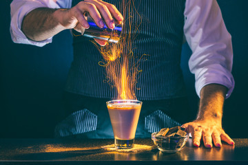 Bartender making sparkling Baileys comet cocktail on fire