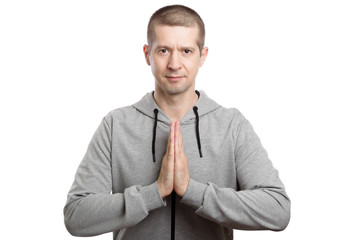 traditional Asian greeting, apology. The man bows, folding his palms of his hands together. A look into the camera. Dressed in sportswear. Isolated