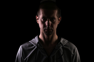 Obraz premium dark silhouette of a man on a black background, a glance at the camera. Dressed in sportswear. Isolated