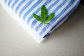 
white and striped fabric with fresh hemp leaves. The concept of using hemp for making fabrics and clothes