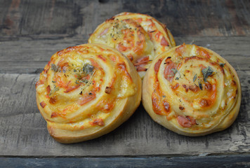 Three homemade pizza rolls with cheese, ham and spelt flour on the rustic wooden table
