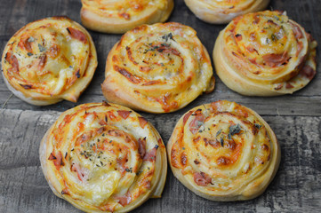 Homemade pizza rolls with mozzarella, ham and spelt flour on the rustic wooden table