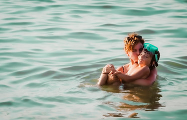 mom and son playing in the sea. Cute European boy in the sea with his mother. They are having fun during their holidays on the seacoast.