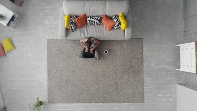 top view, young woman sitting at floar and working on her laptop at home. 