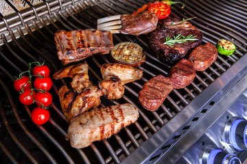 different types of meat with tomatoes and zucchini on the grill