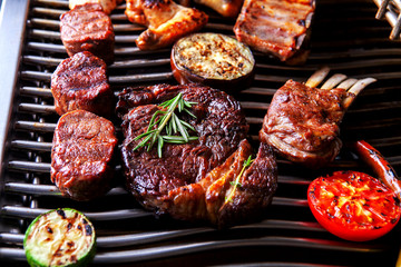 different types of meat with tomatoes and zucchini on the grill