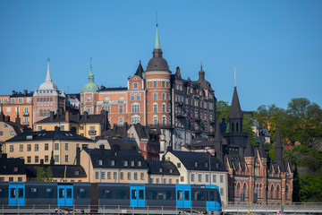 Obraz premium Sunny morning view over old house part of the district of Södermalm, above the waterfront at the bay Riddarfjärden and the sluice part in Stockholm. 
