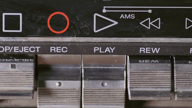 Man finger pressing some buttons on an old retro vintage cassette tape player: play, rewind, fast forward, stop