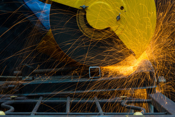Worker using electric grinder machine cutting steel. Steel cutting machine.