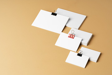Pile of white businesscards with a clip on beige background