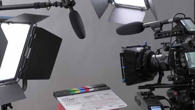 Push in and pull out shot moving through a professional video production film set with camera, lights, and microphone all set up for an interview in a studio setting.