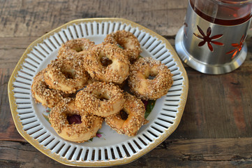 Traditional Middle eastern homemade salty ring cookies with sesame and cumin, cachkitas, on the vintage plate with tea in traditional cup