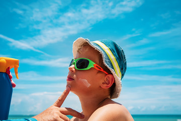 sun protection - parent put suncream on kid face at beach