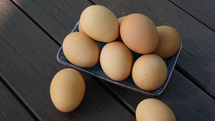 a pile of brown eggs on a plate and two brown eggs on the table 