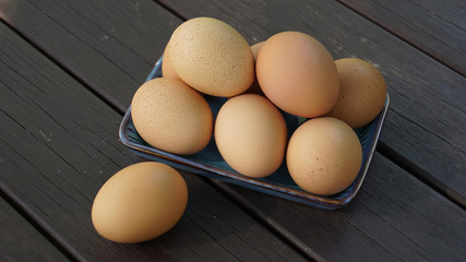 a pile of brown eggs on a plate and one brown egg 